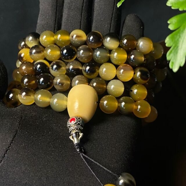 A long 108-bead mala in golden horn with a pale head bead and tassel