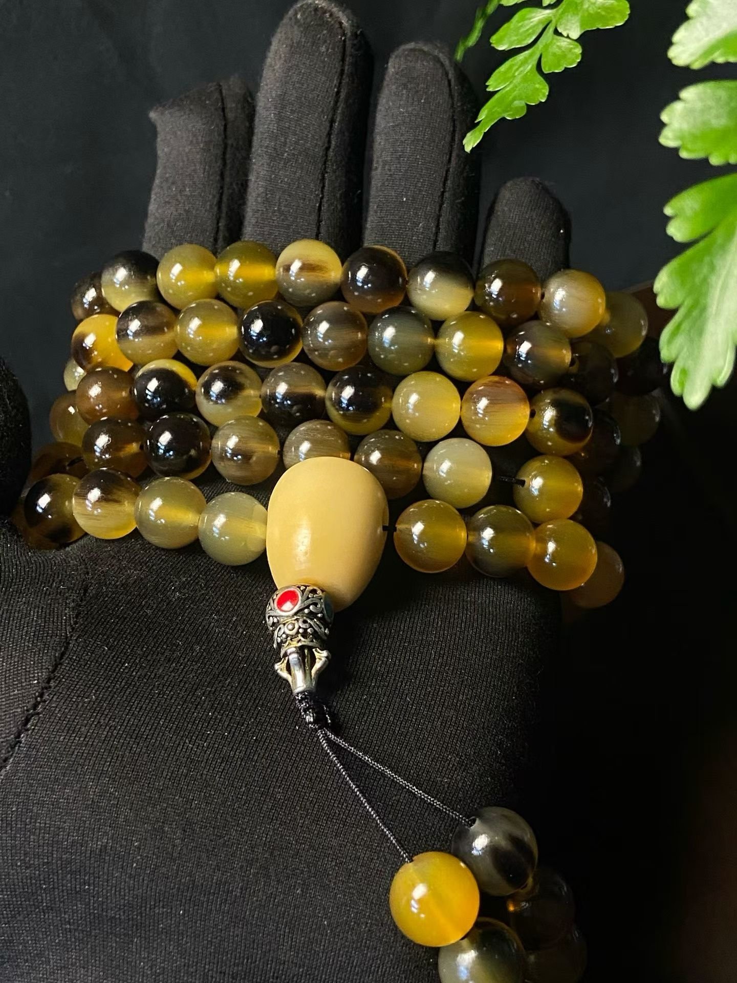 A long 108-bead mala in golden horn with a pale head bead and tassel