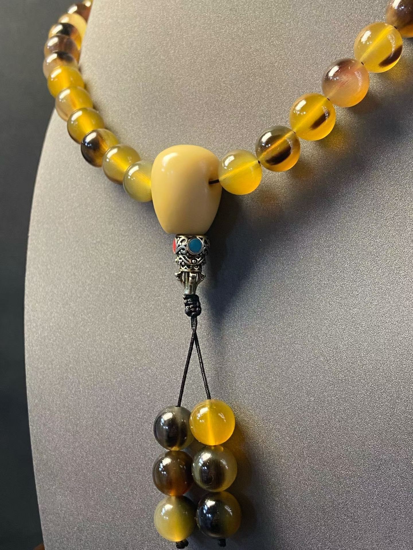 A long 108-bead mala in golden horn with a pale head bead and tassel