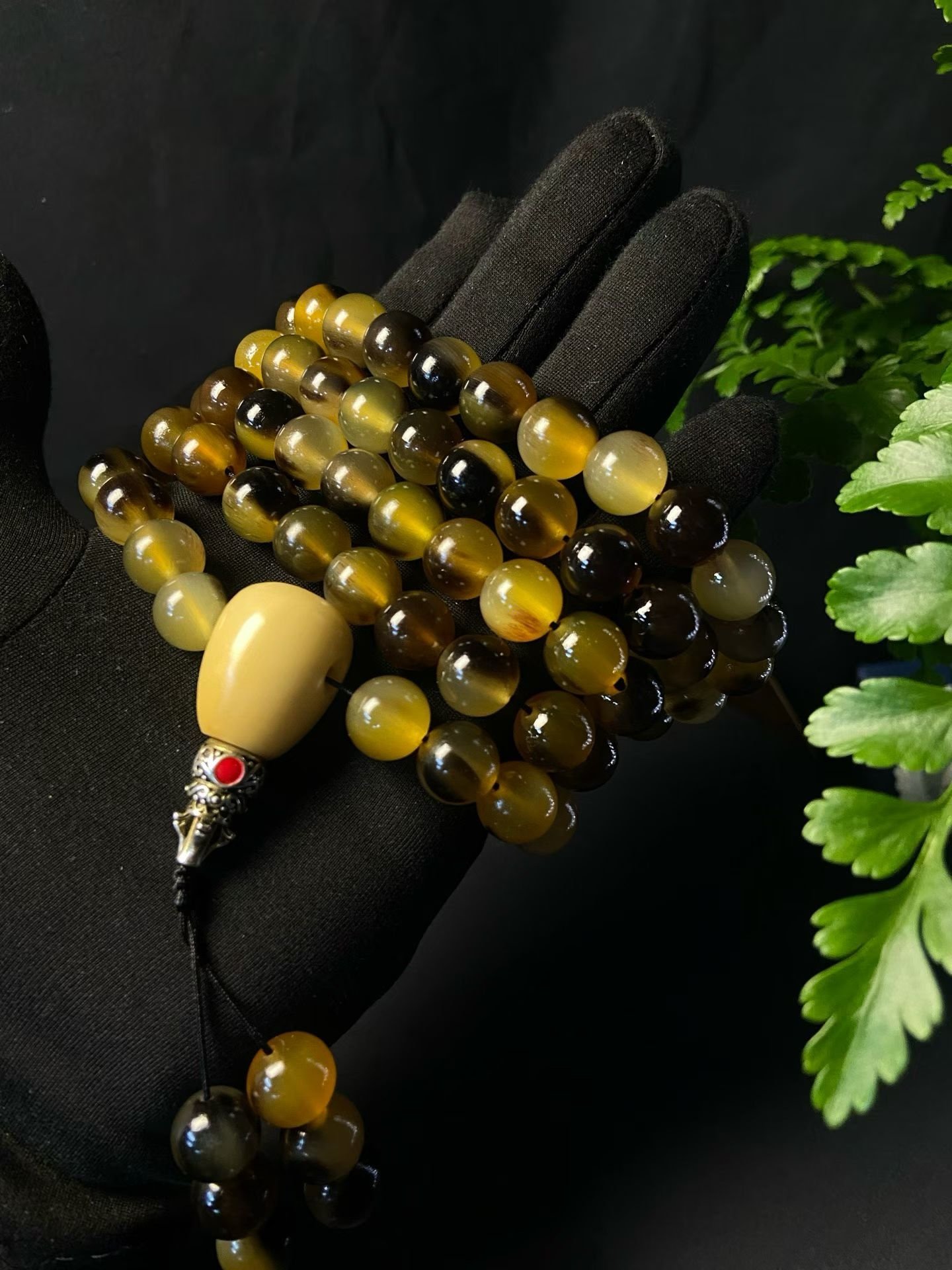 A long 108-bead mala in golden horn with a pale head bead and tassel