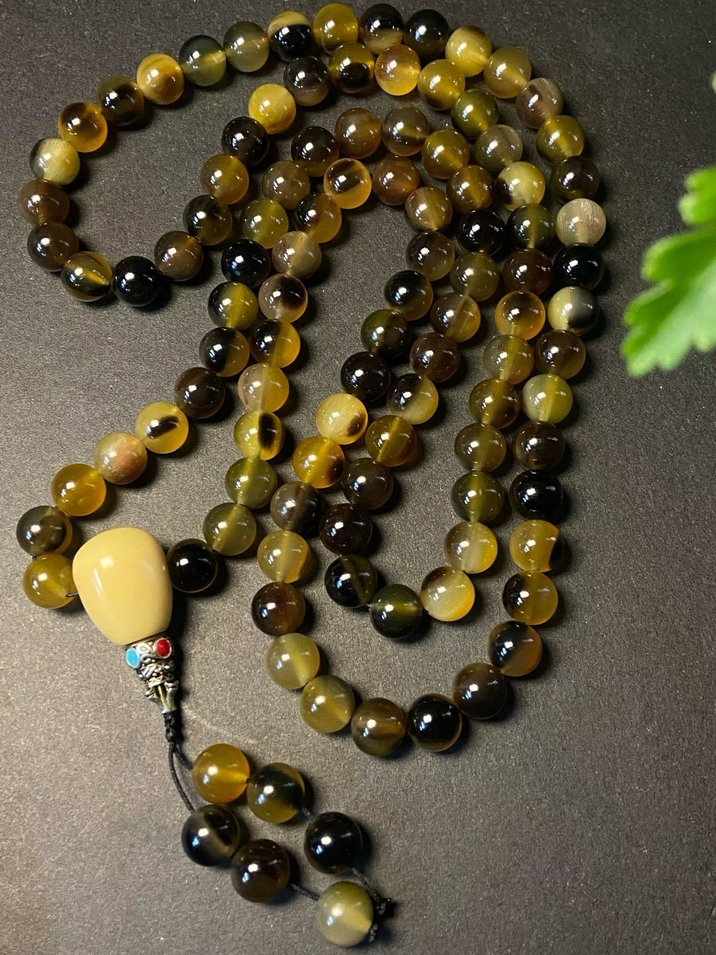 A long 108-bead mala in golden horn with a pale head bead and tassel