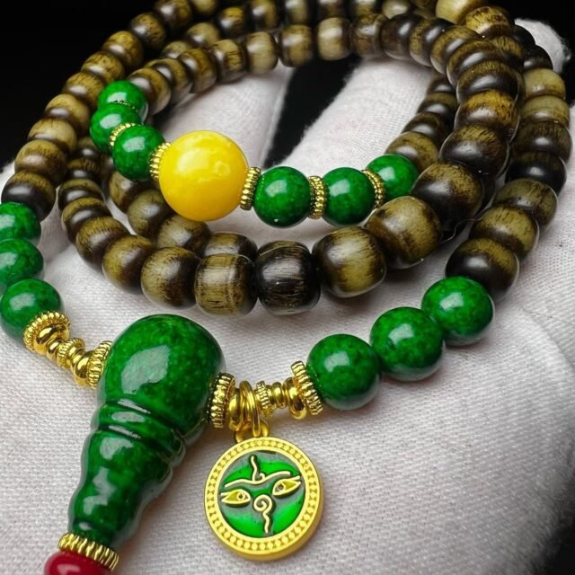 108-bead dark mala with a green gourd pendant resting on a white cotton glove