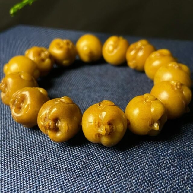 Bracelet of amber-yellow beads, each carved into a laughing face