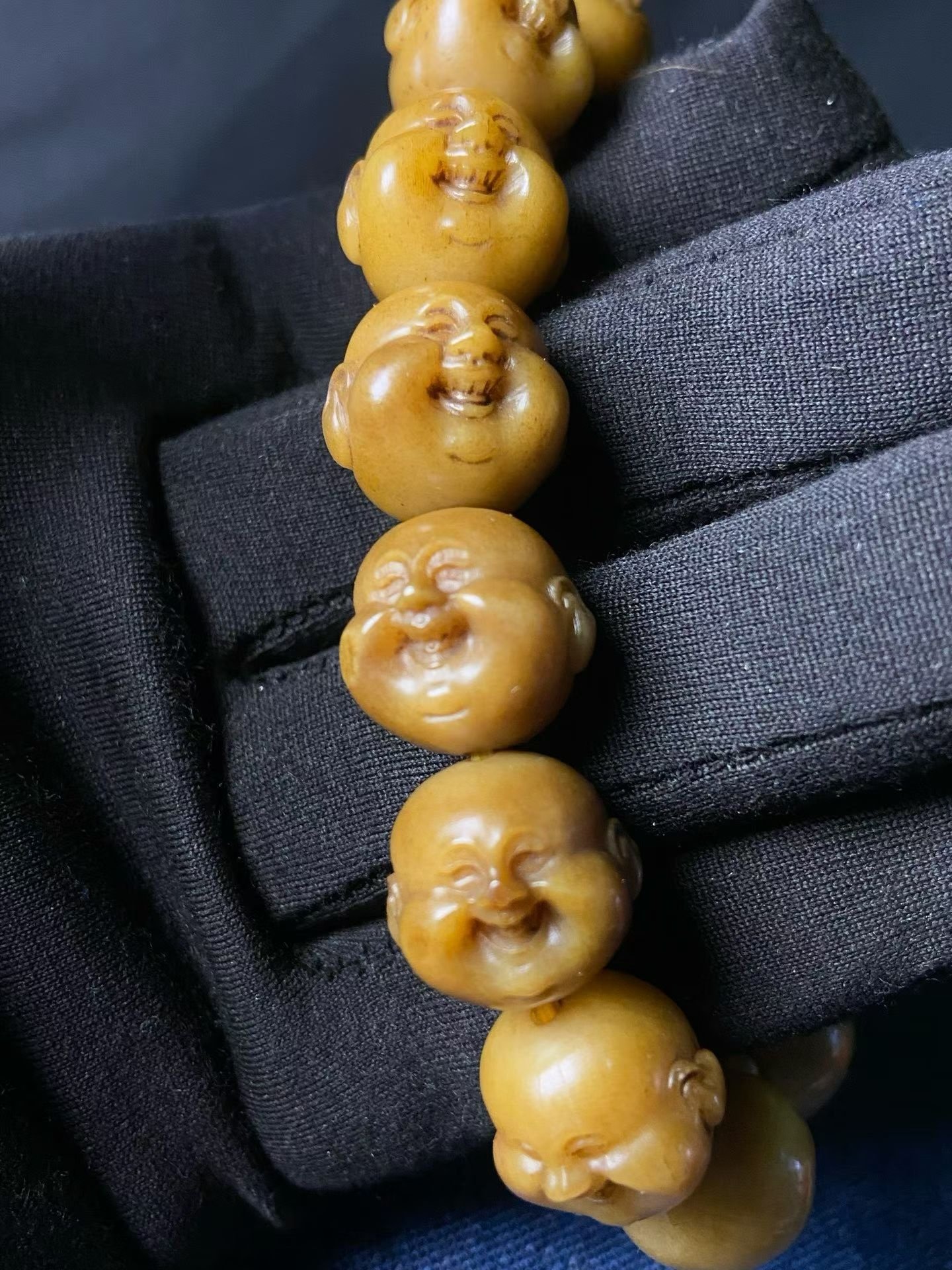 Bracelet of amber-yellow beads, each carved into a laughing face