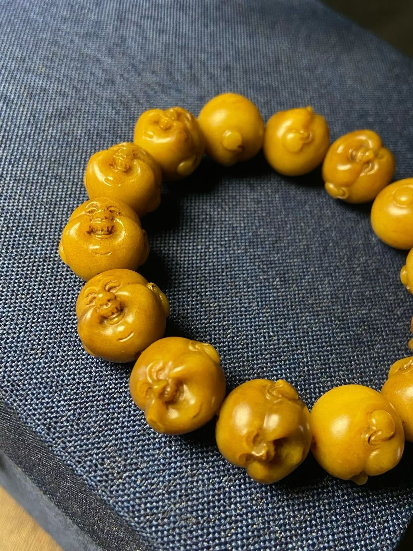 Bracelet of amber-yellow beads, each carved into a laughing face