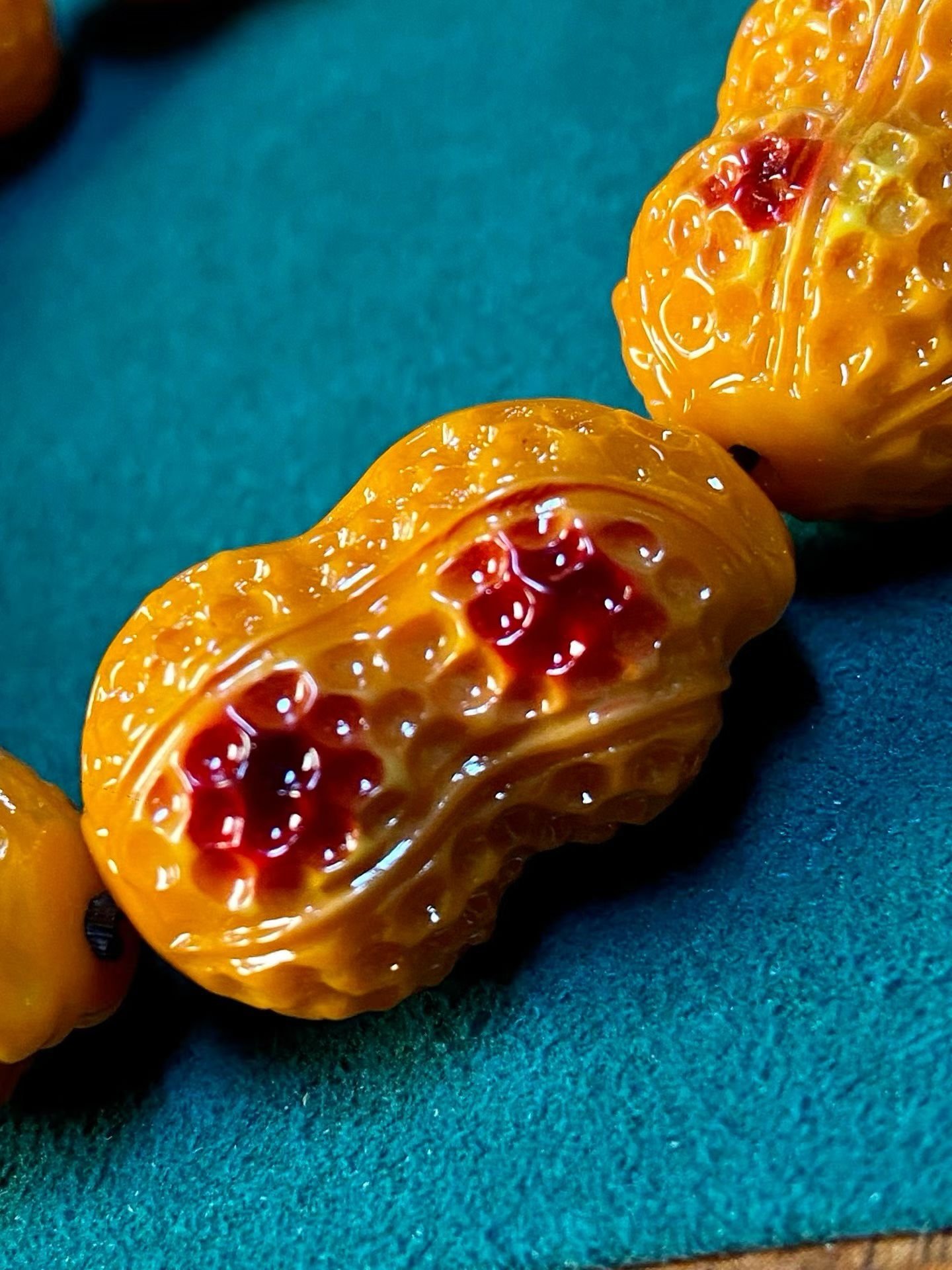 Bracelet of orange peanut-shaped carved beads with red dots, in a bamboo box