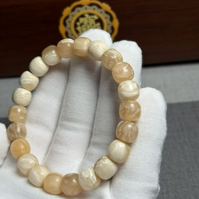Bracelet of small cream beads with shallow carved relief patterns
