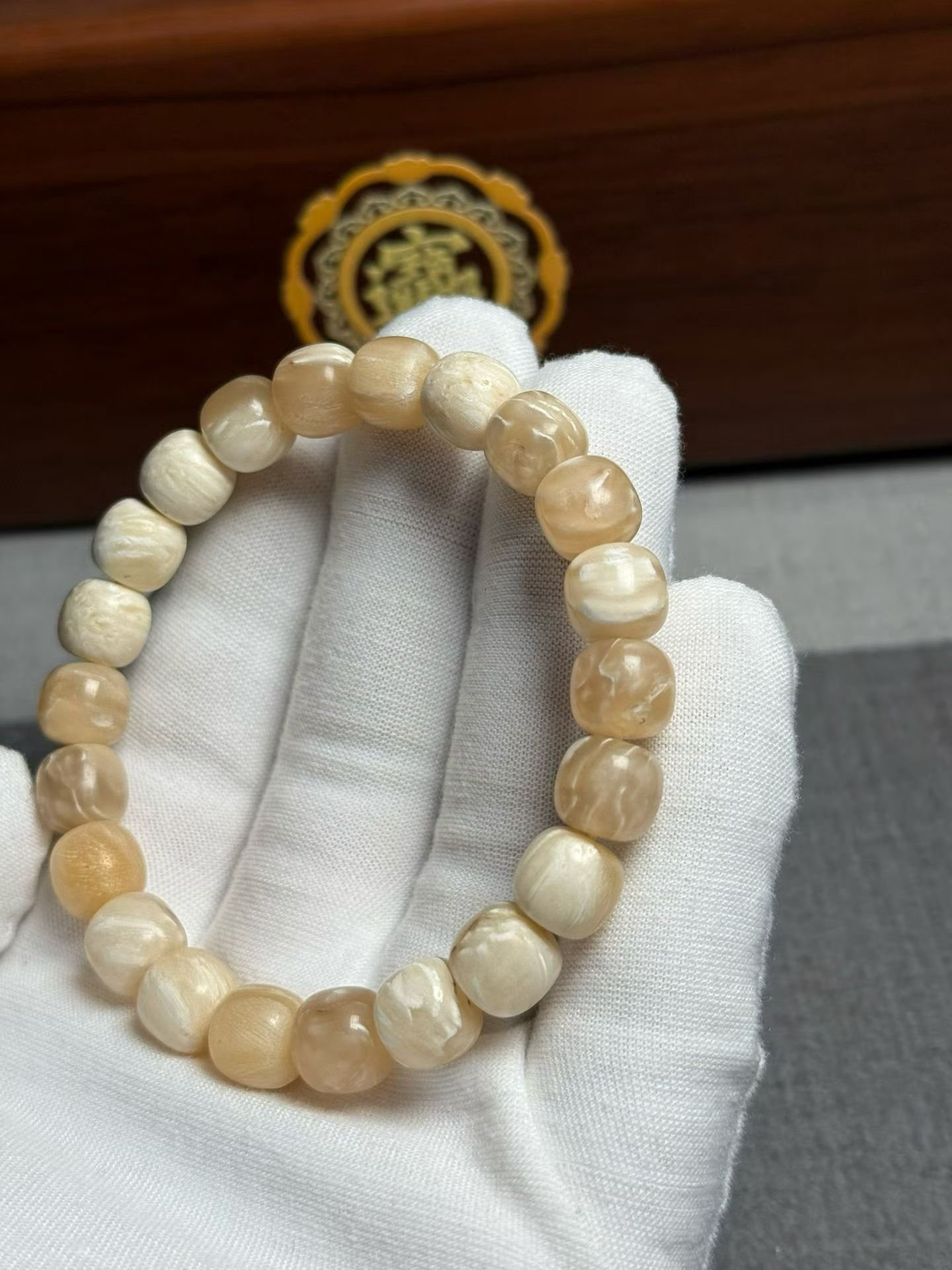 Bracelet of small cream beads with shallow carved relief patterns