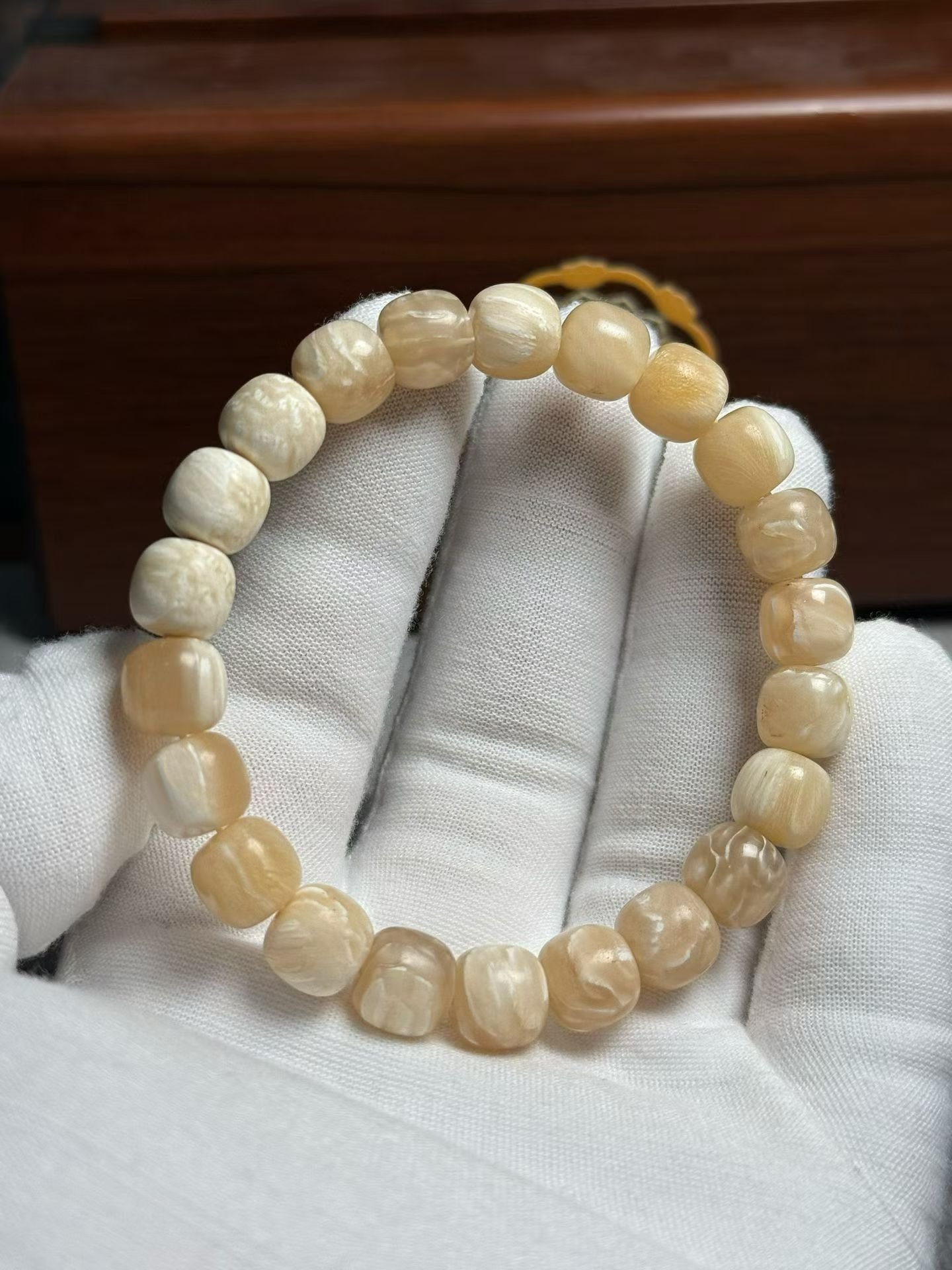 Bracelet of small cream beads with shallow carved relief patterns