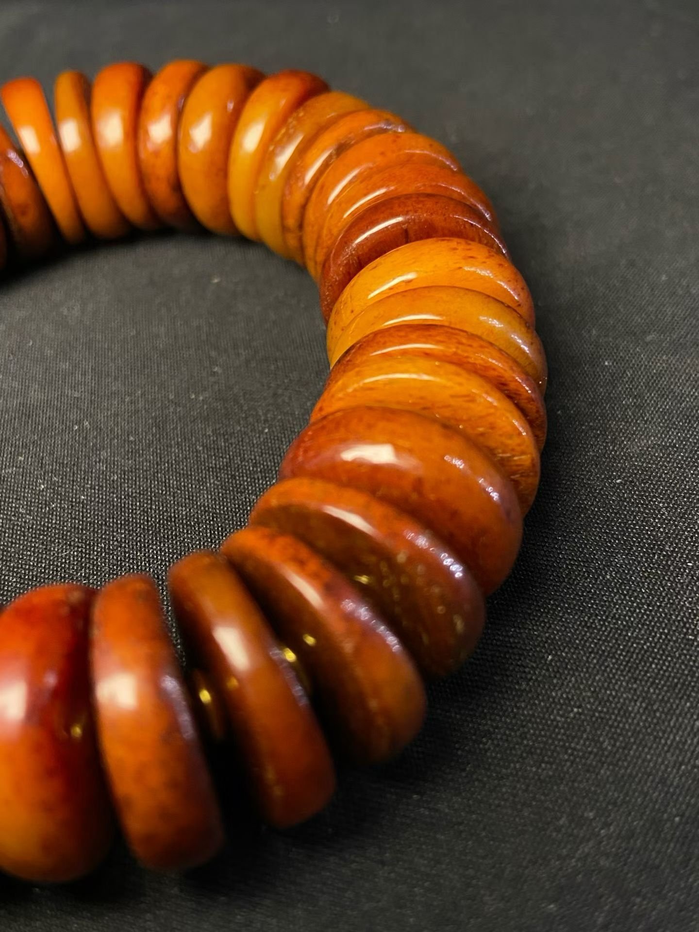 Stacked amber disc beads with a carved buddha head and a silvered vajra pendant