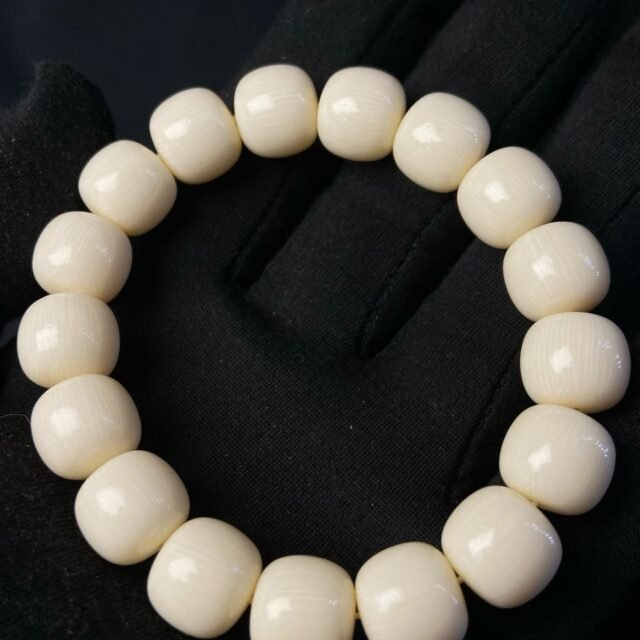 Cream barrel-shaped beads each with a single dark eye-shaped marking