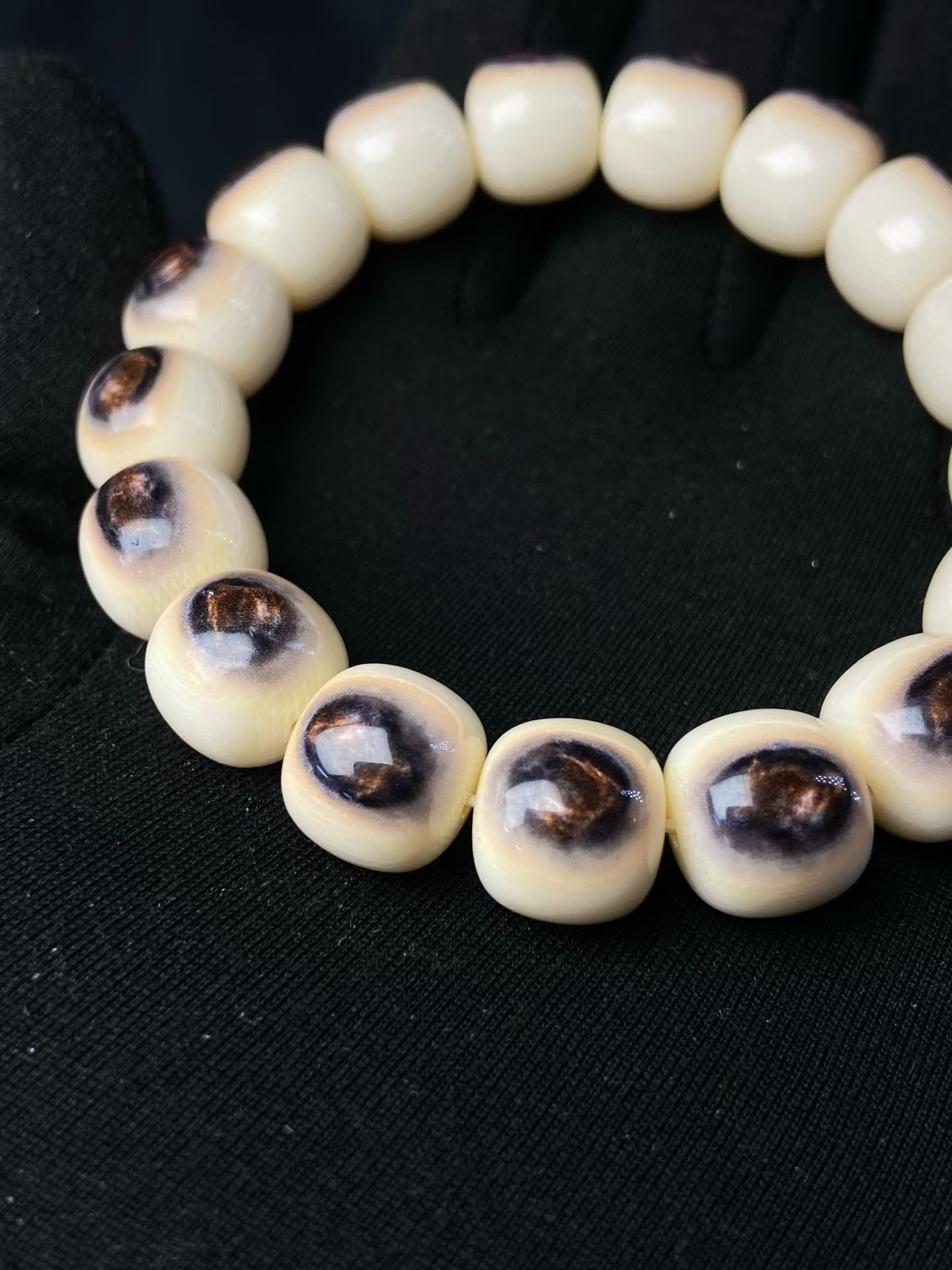 Cream barrel-shaped beads each with a single dark eye-shaped marking