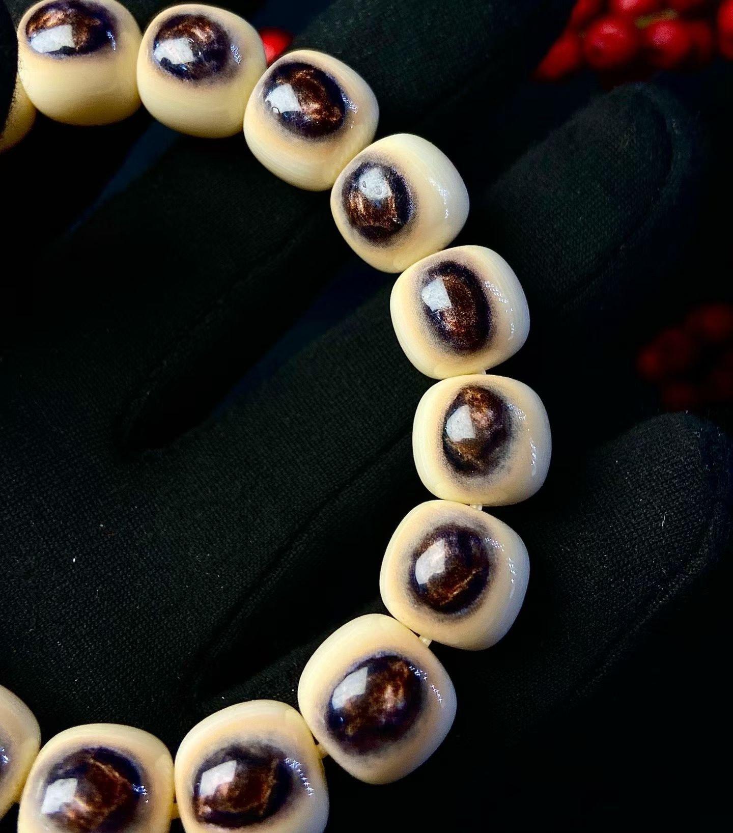 Cream barrel-shaped beads each with a single dark eye-shaped marking