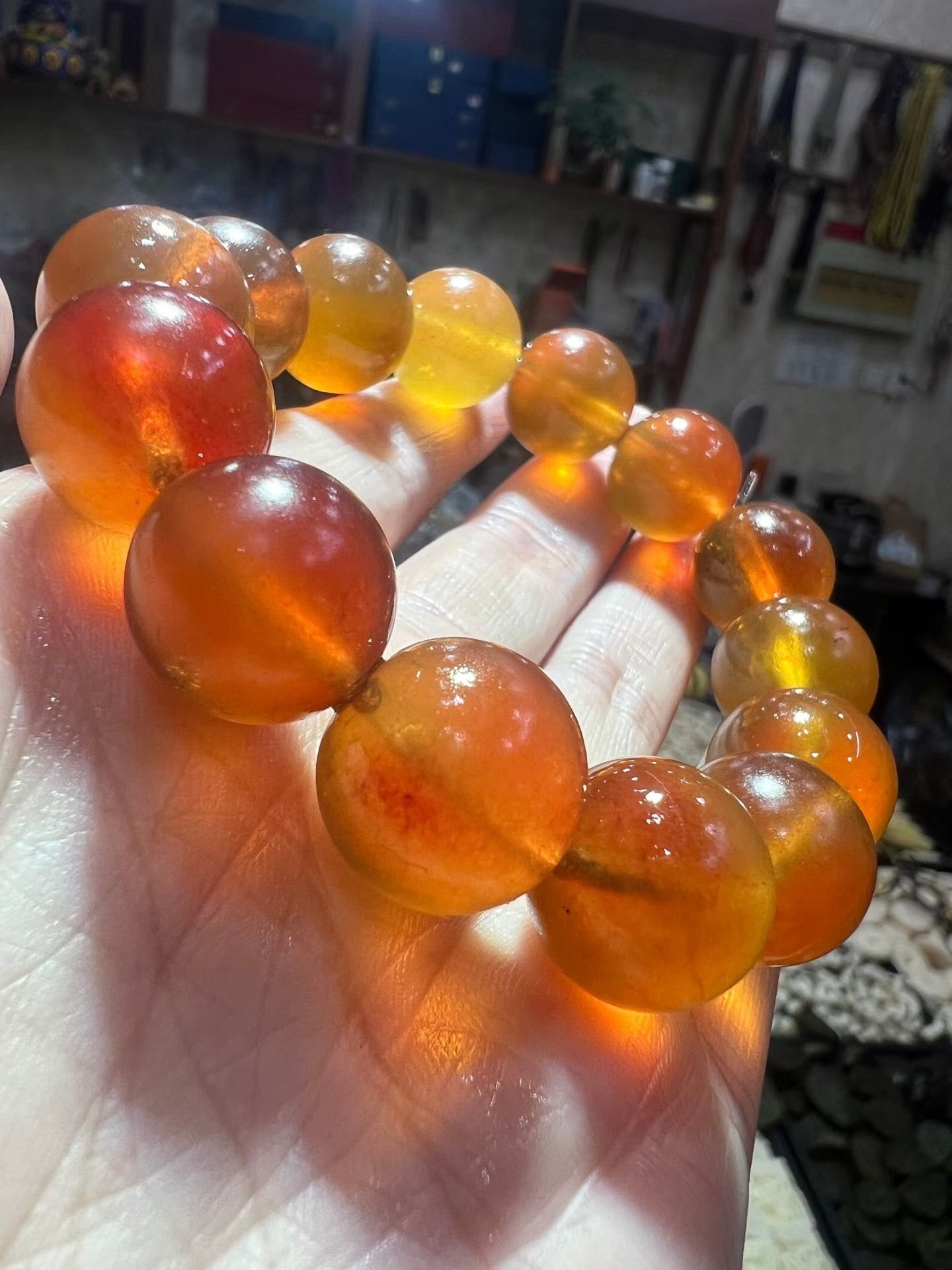Translucent honey-coloured amber bracelet held in a hand with light passing through