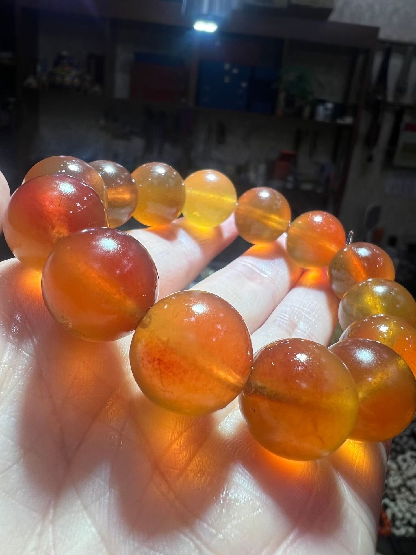 Translucent honey-coloured amber bracelet held in a hand with light passing through