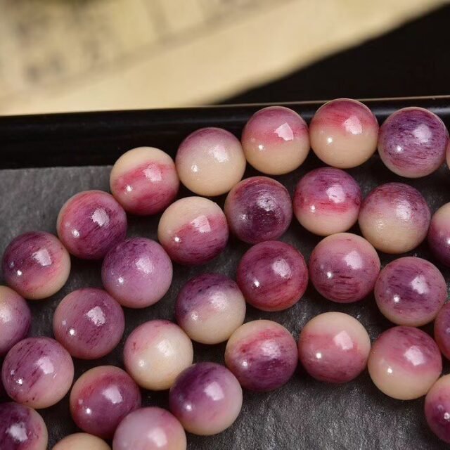 A 108-bead mala in mottled pink and purple stone on a dark stand