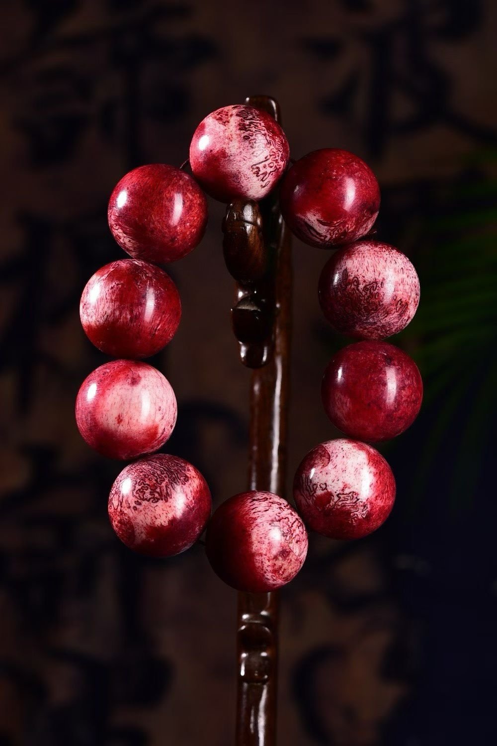 Deep red bracelet with white cloud-like veining, on dark wood